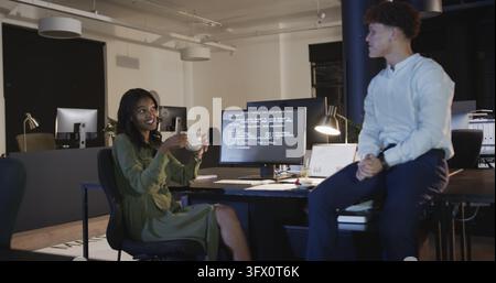Différents collègues collaborant sur du code informatique dans un bureau moderne pendant le travail de nuit. Technologie, travail d'équipe, collaboration, logiciel, programmation, inn Banque D'Images