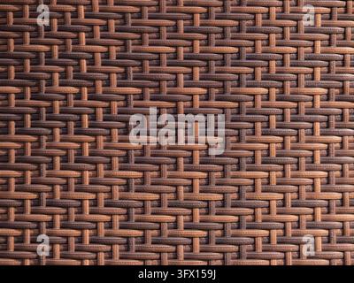 Matériau en rotin synthétique créant un motif entrelacé sans couture avec des nuances contrastées de brun et de beige, offrant une surface durable et décorative Banque D'Images