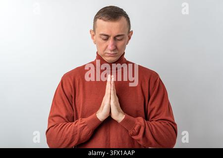 Homme trouvant la paix intérieure et la connexion spirituelle, debout les mains jointes dans un geste respectueux, les yeux fermés dans une profonde concentration et Banque D'Images