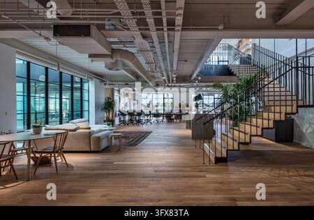 Intérieur du studio de design IDEO à Londres à Clerkenwell, comprenant un espace de travail ouvert, un sol en bois, des services exposés et un escalier en acier. Banque D'Images