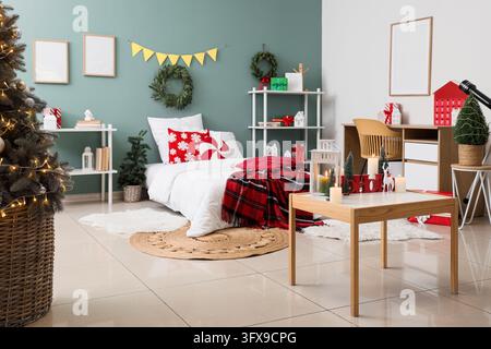 Intérieur d'une maison de Noël, chambre confortable décorée pour les fêtes hivernales avec un arbre festif, une parure de lit à carreaux rouges et des ornements saisonniers dans un appartement moderne Banque D'Images