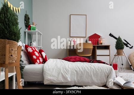 Intérieur de maison de Noël, chambre confortable décorée pour les fêtes hivernales avec une parure de lit festive, un calendrier de l'Avent et un télescope pour l'observation des étoiles dans la chambre Banque D'Images