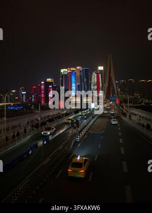 Trafic sur un pont à haubans en direction d'un ciel nocturne lumineux à Chongqing. Banque D'Images