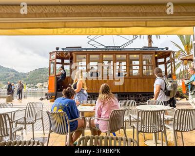 Tramway orange à Port de Soller Mallorca avec des passagers et des gens aux tables du café Banque D'Images