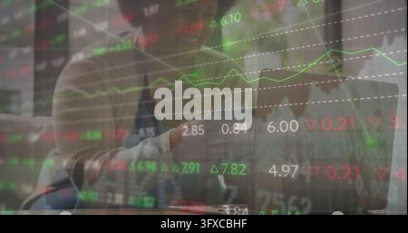 Femme mi-adulte pointant du doigt en cardigan par-dessus une chemise, analysant un ordinateur portable à une table de bureau, superposition de marché. Finance, analyse, collaboration, tableau de bord, données Banque D'Images
