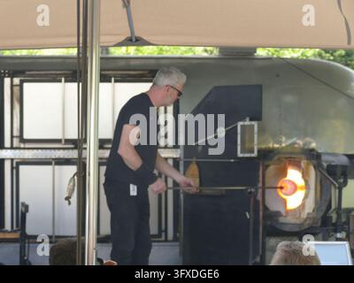 SEATTLE - 25 AVR 2025 - Souffleur de verre façonnant soigneusement une pièce de verre en fusion avec une canne à souffler dans un four à verre dans un atelier de soufflage de verre, créant Banque D'Images