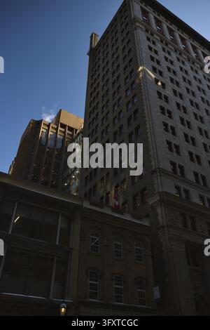 Vue ascendante des bâtiments de bureaux historiques et modernes du centre-ville de Toronto, comprenant un grat-ciel en pierre aux détails architecturaux ornés, un drapeau canadien et une épingle Banque D'Images