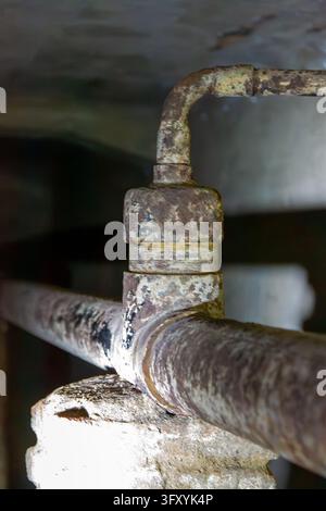 Cette photographie macro verticale se concentre sur un joint de tuyau en métal fortement rouillé à l'intérieur du sous-sol souterrain de Lawang Sewu à Semarang. Le faible d Banque D'Images