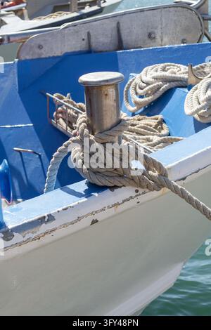 Corde d'amarrage enroulée autour d'un poteau métallique sur un bateau patiné par les intempéries Banque D'Images