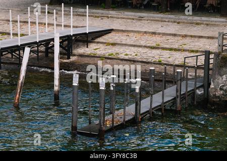 Bellagio, Italie – 1er juin 2026 : Passerelle flottante avec poteaux d'amarrage érodés dans les eaux du lac de Côme à Bellagio, embarcadère pour les services de ferry Banque D'Images