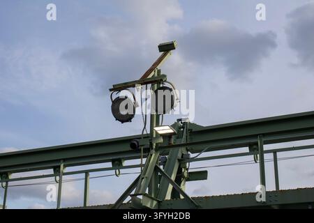 New York City, États-Unis – 19 mars 2024 : Paire de projecteurs anciens montés sur une poutre en acier verte contre un ciel nuageux à Pier 57. Banque D'Images