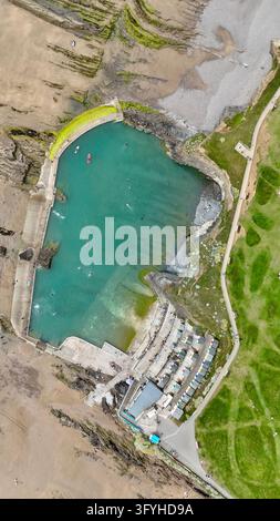 Vue aérienne par drone de dessus de la Bude Sea Pool, nageurs et cabanes de plage à côté de Summerleaze Beach dans le Cornwall, Angleterre Banque D'Images