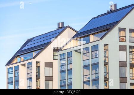 Un immeuble d'appartements contemporain avec de grandes fenêtres et un toit incliné recouvert de panneaux solaires, mettant en valeur des solutions d'énergie verte et une architecture éco-responsable Banque D'Images