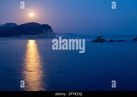 Une pleine lune illumine les eaux calmes de la mer Adriatique, projetant un reflet miroitant. Au premier plan, les îles rocheuses du Monténégro apparaissent Banque D'Images