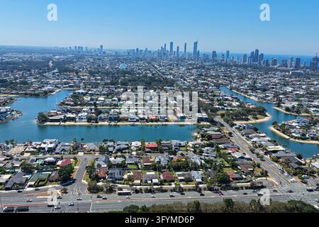 Vue aérienne du quartier résidentiel en bord de canal de Broadbeach avec des maisons, des voies d'eau et la ligne d'horizon lointaine de Gold Coast sous un ciel bleu clair Banque D'Images