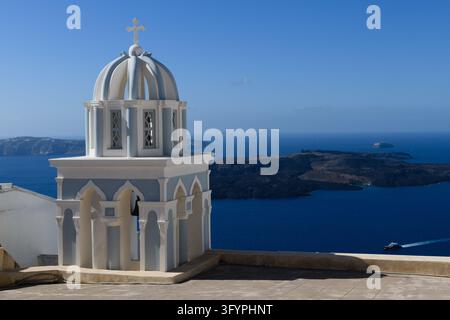 Dôme bleu emblématique et clocher des Trois Cloches de l'église de Fira à Santorin surplombant la caldeira, capturant l'héritage grec traditionnel, la foi, un Banque D'Images