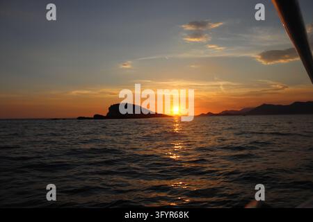 Couchant doré serein sur la mer Adriatique près de Cavtat, Croatie. Le soleil touche l'horizon derrière les collines lointaines créant un long reflet doré brillant Banque D'Images