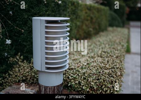 Lampadaire moderne de jardin extérieur à côté d'une haie paysagée en France Banque D'Images