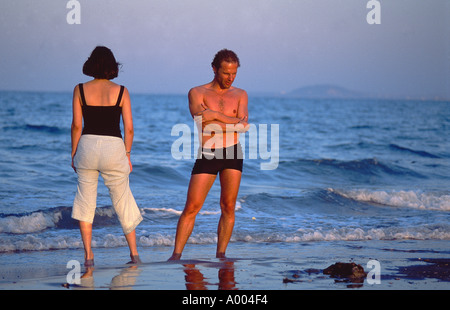 Couple en vacances - debout sur la plage regardant dans différentes directions Banque D'Images