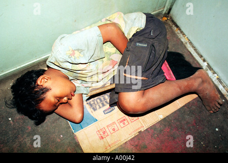 Les jeunes sans-abri sale garçon dort sur du carton dans l'un des trains il balaie pinceau propre en toute sécurité entre les jambes est de java Banque D'Images