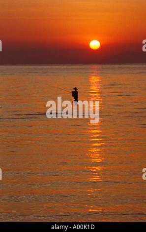 Le pêcheur local avec la tige est la pêche dans la mer par la silhouette du beau coucher de soleil à Bali Indonésie Lovina Banque D'Images