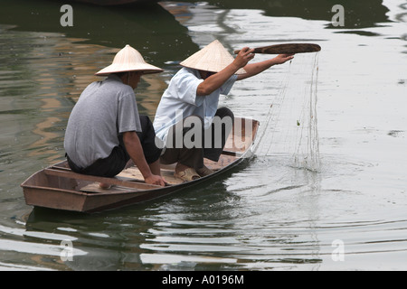 Deux hommes de pêche petit bateau à aubes et net Rivière Yen menant à la Pagode des parfums près de Hanoi Vietnam du Nord Banque D'Images