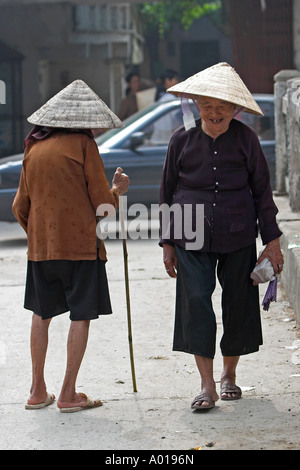 Deux personnes âgées femmes chapeau conique salue en passant sur le pont en Yen ville près de Pagode des parfums à l'extérieur du nord Vietnam Hanoi Banque D'Images