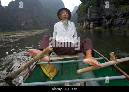 Aviron pied inhabituelle Tam Coc domaine de la rivière Ngo Dong près de Ninh Binh au nord Vietnam Banque D'Images