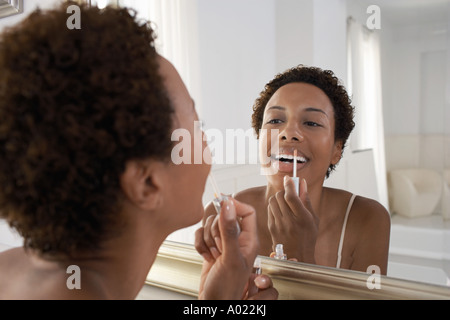 Woman applying lip gloss en miroir, à la maison Banque D'Images