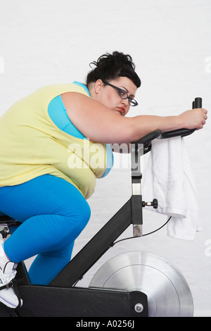 Femme de l'embonpoint on Exercise Bike Banque D'Images