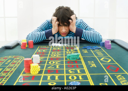 Jeune homme frustré at roulette table Banque D'Images