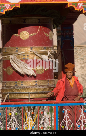 Un vieux moine avec un chapeau faisant tourner un grand moulin à prières dans le village de Karsha, Zanskar, Ladakh, Jammu Cachemire, Inde. Banque D'Images