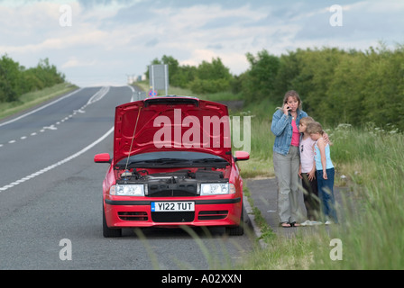 Famille avec une voiture en panne dans une aire de solliciter de l'aide sur un téléphone mobile Banque D'Images