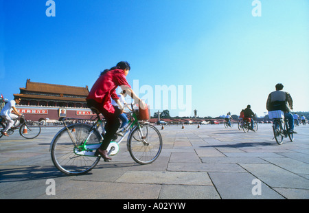 Au début de l'heure de pointe du matin à la place Tiananmen, jeune femme en veste rouge à vélo au travail Beijing Chine Banque D'Images