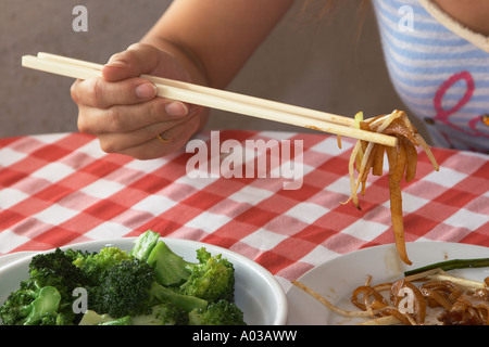 Femme à l'aide de baguettes pour manger des mets chinois , Hong Kong Banque D'Images