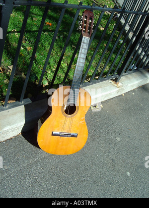 Scène urbaine de guitare appuyé contre une clôture en fer Banque D'Images