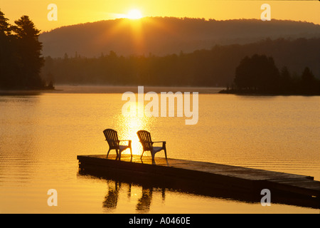 Canada Ontario Oxtongue Lake chaises Adirondack sur quai au lever du soleil Banque D'Images