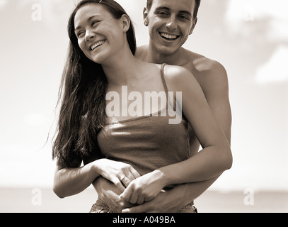Young couple embracing standing outdoors laughing Banque D'Images