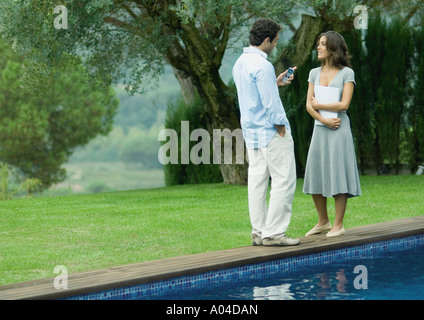 L'homme et la femme debout près du bord de la piscine avec des documents et cell phone Banque D'Images