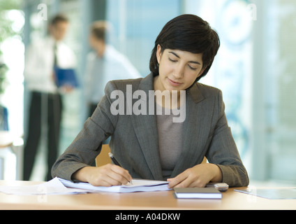 Businesswoman sitting at desk, écriture Banque D'Images