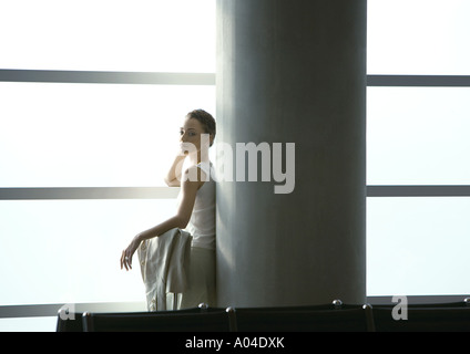 Woman leaning against column in airport Banque D'Images