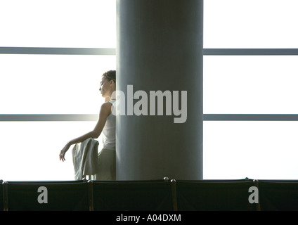 Woman leaning against column in airport Banque D'Images