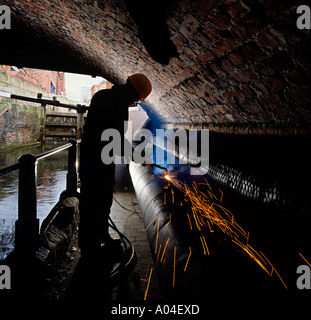 L'homme de l'industrie à l'aide d'acétylène Manchester Oxy coupage sous pont-canal de Bridgewater Banque D'Images