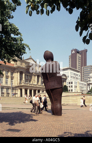 People & six tonnes penchée en fer sculpture Iron Man par sculpteur Antony Gormley urbain piétonnier Victoria Square Birmingham West Midlands Angleterre Royaume-Uni Banque D'Images