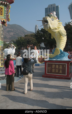 La prospérité de poissons dh REPULSE BAY HONG KONG Les touristes en jetant de l'argent en statue de Tin Hau bouche pour porter chance femme Banque D'Images
