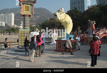 dh Fish of Prosperity REPULSE BAY HONG KONG touristes jeter de l'argent dans l'embouchure de la statue de Tin Hau pour apporter bonne chance visite de tao Banque D'Images