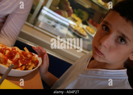 Boy eating chips avec de la sauce tomate Banque D'Images