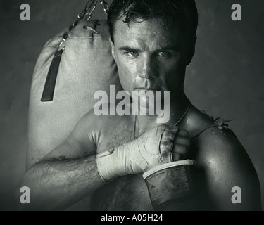 Portrait d'une sueur male boxer avec des gants de boxe sac de frappe enregistrées et les mains Banque D'Images