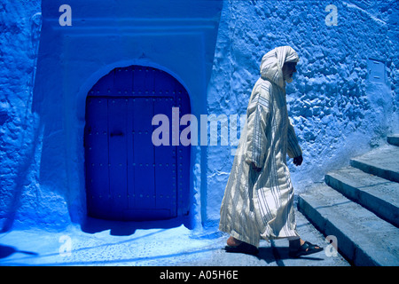 Musulman marocain dans un burnoose blanc robe jellaba jusqu'à pied des mesures contre la paroi d'argile bleu Maroc Chefchaouen Banque D'Images