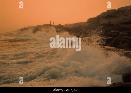 Silhouette d'un couple dans la distance debout sur un rocher surplombant l'eau à la plage nord-est Banque D'Images